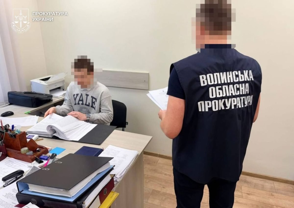 Затриманий за столом з документами, поруч працівник прокуратури